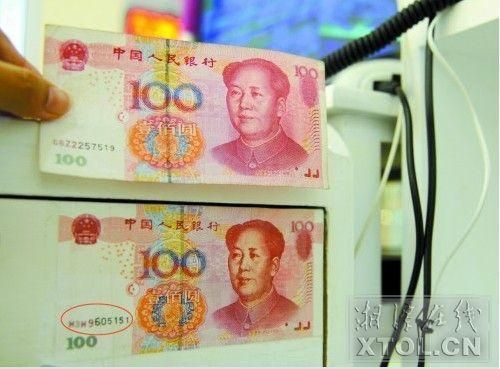 编号为M3W9605151的假币(下),正面和真币几乎完全一样,店家将它张贴在收银柜外,提醒自己不要再上当。 (记者 张哲 摄)