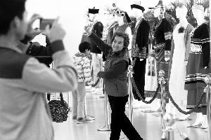 一位阿姨在身着少数民族服装的模特前摆造型。